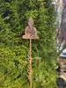A garden decoration featuring a Buddha statue and a rain gauge, set against a green hedge. Náhled obrázku produktu