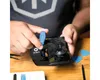 A person's hands are using a tool to repair a smartphone. Produktbild-Vorschau