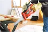 A person wearing gloves is using a Black & Decker reciprocating saw to cut a wooden plank on a workbench. Anteprima dell’immagine prodotto