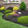 A garden bed with black metal edging, surrounded by grass, mulch, and various plants including green bushes, yellow foliage, and pink flowers. Produktbild-Vorschau