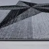 A close-up view of a grey rug with a geometric black pattern. Voir les images du produit