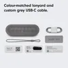 A flat lay of the Beats Pill x Kim Kardashian speaker and its accessories, including a charging cable, lanyard, and informational cards. Podgląd zdjęcia produktu