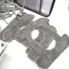 Several gray microfiber cleaning pads are stacked on a white surface, with a power cord and adapter visible in the background. Produktbild-Vorschau