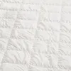 A close-up, overhead view of a white quilted blanket. Produktbild-Vorschau