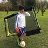A young boy is playing soccer in a backyard with a soccer goal. Produktbild-Vorschau
