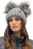 A woman wearing a gray knitted winter hat with two faux fur pom-poms.