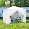 A white pop-up canopy tent set up on grass next to a vintage trailer, with a table and chairs inside. Produktbild-Vorschau