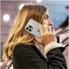 A woman is holding an iPhone 14 Pro Max in a clear case to her ear, seemingly in a public indoor space with escalators in the background. Anteprima dell’immagine prodotto