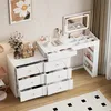 A white vanity table with a lighted mirror and multiple drawers, filled with makeup and accessories. Anteprima dell’immagine prodotto