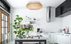 A modern kitchen and dining area with a table set for a meal, featuring a ceiling lamp and kitchen appliances. Produktbild-Vorschau