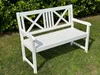 A white wooden garden bench sits on a grassy lawn with a hedge in the background. Produktbild-Vorschau