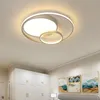 A modern ceiling light fixture with a circular design, installed on a white ceiling above a wardrobe and artwork. Náhled obrázku produktu