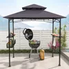 A grill pavilion set up outdoors with a grill, accessories, and a scenic background. Produktbild-Vorschau