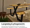 A wooden table and bench set with black metal legs, set up outdoors on a patio with a potted plant and some flowers. Anteprima dell’immagine prodotto