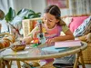 A young girl is playing with a LEGO Creator Tropical Ukulele set in a living room setting. Náhled obrázku produktu