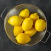 Lemons in a metal colander on a dark textured surface. Anteprima dell’immagine prodotto