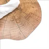 A close-up of a round placemat with a wood log pattern, showing water droplets on its surface and a white cloth partially covering it. Produktbild-Vorschau