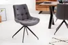 A grey upholstered dining chair with a black metal base is shown in a room with a wooden dining table and cabinet in the background. Produktbild-Vorschau