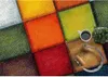 A colorful, checkered rug with a mug of coffee, headphones, and a small plant on it. Produktbild-Vorschau