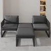 A modern gray outdoor furniture set with two armchairs and two ottomans, arranged on a concrete floor in front of a wall with shelves. Produktbild-Vorschau