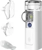 A white, portable nebulizer with two masks and a mouthpiece, displayed against a white background. Náhled obrázku produktu