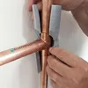 Hands are shown installing a gray foam pipe insulation around a copper pipe fitting. Produktbild-Vorschau