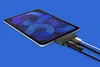 A tablet with a hub attached, connected to cables, on a blue background. Voir les images du produit