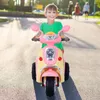 A young boy rides a pink and yellow electric toy motorcycle on a paved path outdoors. Náhled obrázku produktu
