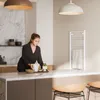 A woman is preparing food in a modern kitchen with marble countertops and pendant lights. Produktbild-Vorschau