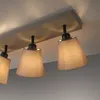 A close-up view of a ceiling light fixture with multiple fabric shades. Produktbild-Vorschau