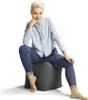 A woman is sitting on a cube-shaped ottoman. Produktbild-Vorschau