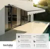 An awning is extended over a patio area next to a sliding glass door, with a pool visible in the background. Text overlays describe product features. Produktbild-Vorschau