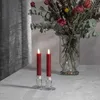 Two red LED candles in glass holders on a table with a bouquet of dried flowers in the background. Produktbild-Vorschau