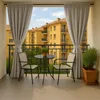 A balcony with a table and chairs, overlooking apartment buildings. Anteprima dell’immagine prodotto
