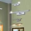 Several wall-mounted lights are displayed on a textured green wall, with framed artwork visible below. Podgląd zdjęcia produktu
