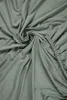 A close-up, swirled view of a green jersey fitted sheet. Produktbild-Vorschau