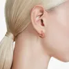 Close-up of a person's ear wearing a heart-shaped earring. Produktbild-Vorschau