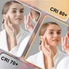 A woman applying cream to her face in front of a mirror, with text overlays indicating CRI ratings. Podgląd zdjęcia produktu