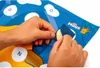 Hands are peeling a sticker from a colorful board game with letters and cartoon characters. Produktbild-Vorschau