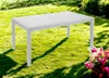 A white rectangular table with a rattan effect is placed on a green lawn in a garden setting, with some pink flowers in the foreground. Produktbild-Vorschau