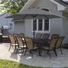 An outdoor patio scene with a table and chairs set up under a large umbrella. Produktbild-Vorschau