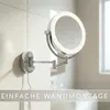 A lighted magnifying mirror mounted on a wall in a bathroom. Produktbild-Vorschau