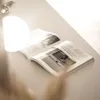 An open magazine is placed on a light-colored surface, illuminated by a bright light source casting a shadow. Produktbild-Vorschau