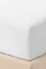 A close-up view of a white fitted sheet on a bed, with a beige bed skirt visible at the bottom. Produktbild-Vorschau