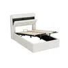 A white upholstered bed frame with the mattress support mechanism raised, revealing storage space underneath. The headboard has a lift-up compartment. Anteprima dell’immagine prodotto