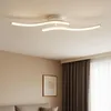 A modern white ceiling light fixture with curved arms is mounted on a white ceiling. Náhled obrázku produktu