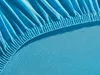 A close-up view of the elasticized edge of a turquoise fitted sheet. Produktbild-Vorschau