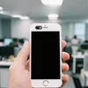 Schwarze Webcam-Abdeckung mit 'D'-Logo auf einem weißen Smartphone, in einer Hand in einem Büro gehalten Produktbild-Vorschau