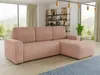 A pink corduroy sectional sofa is placed in a modern living room with large windows overlooking a natural landscape. A bookshelf filled with decorative items and a potted plant are visible in the background. Produktbild-Vorschau