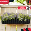 A black planter box filled with purple flowers and green foliage, attached to a wooden fence. Náhľad obrázku produktu